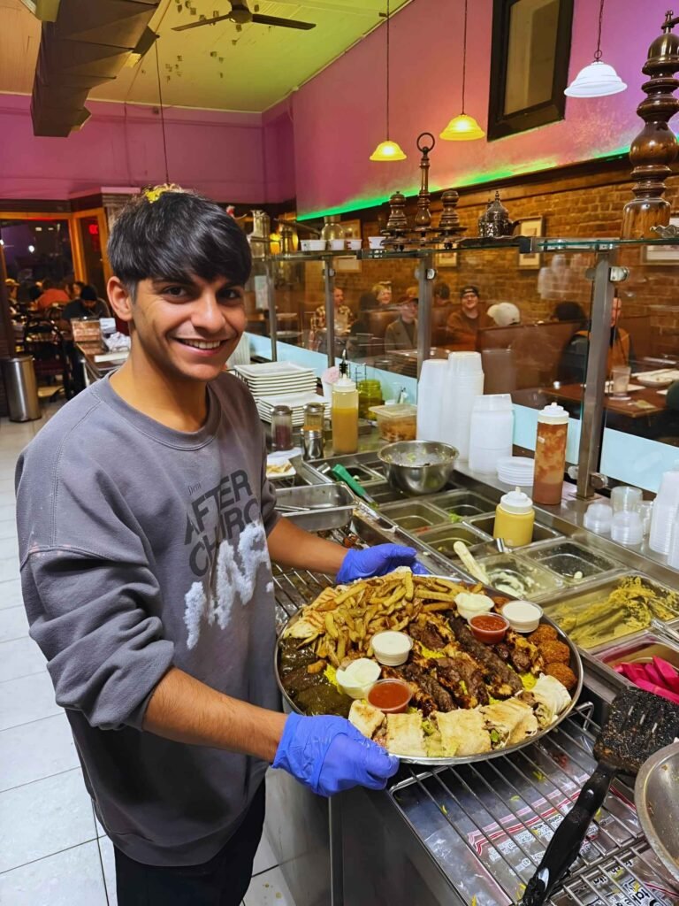 Smiling employee at That Lebanese Place holding the Family Tray, ready to serve guests authentic Lebanese food with warmth and hospitality.