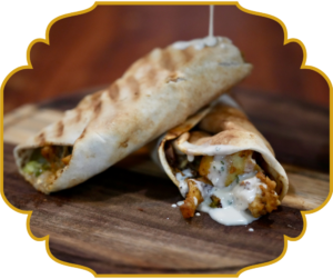 Chicken shawarma wrap with garlic sauce drizzling from grilled pita bread at That Lebanese Place