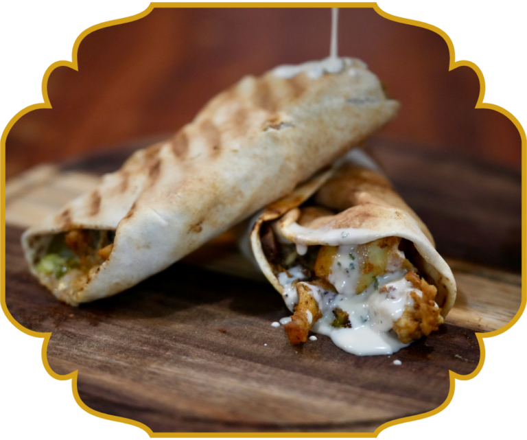 Chicken shawarma wrap with garlic sauce drizzling from grilled pita bread at That Lebanese Place